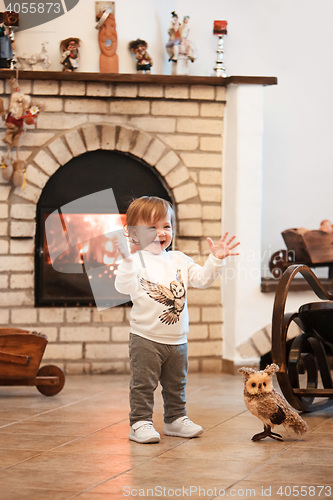 Image of Happy child little girl standing at home against fireplace