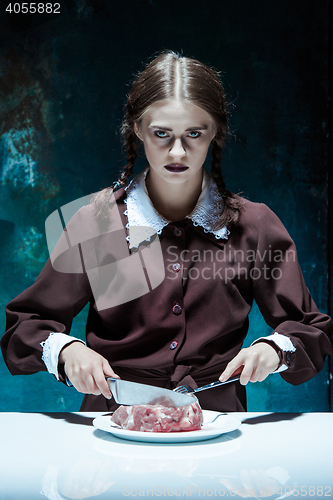 Image of Bloody Halloween theme: crazy girl with a knife, fork and meat