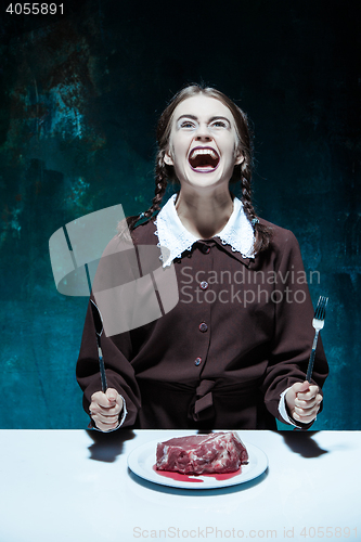 Image of Bloody Halloween theme: crazy girl with a knife, fork and meat