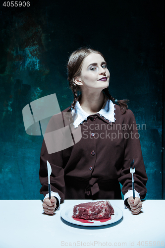 Image of Bloody Halloween theme: crazy girl with a knife, fork and meat