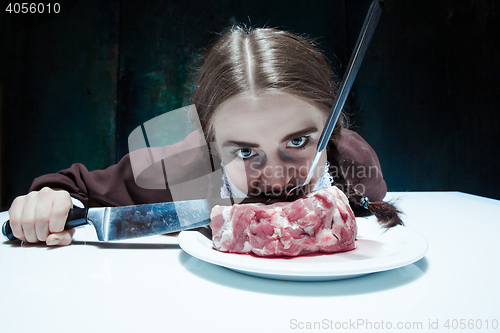 Image of Bloody Halloween theme: crazy girl with a knife, fork and meat