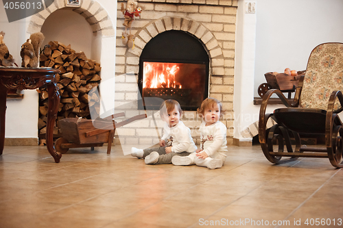 Image of The two little girls sitting at home against fireplace