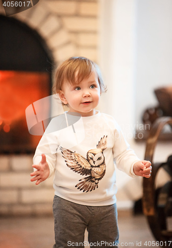 Image of Happy child little girl standing at home against fireplace
