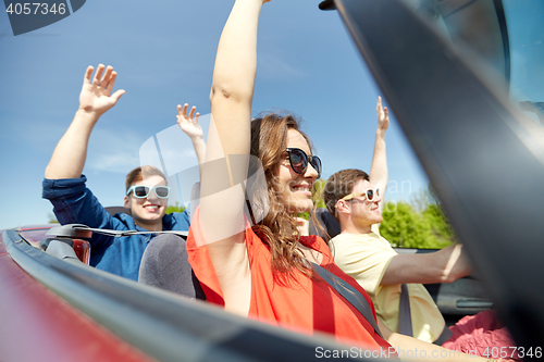 Image of happy friends driving in cabriolet car at country