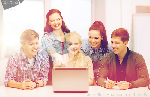 Image of smiling students looking at laptop at school