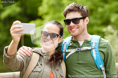 Image of couple with backpacks taking selfie by smartphone