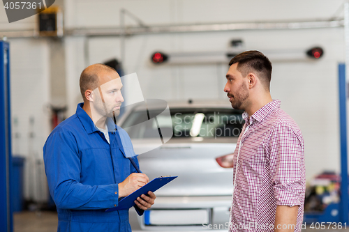 Image of auto mechanic with clipboard and man at car shop