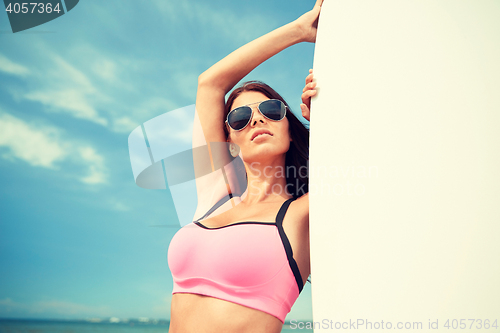 Image of smiling young woman with surfboard on beach