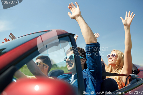 Image of happy friends driving in cabriolet car at country