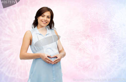 Image of happy pregnant woman making heart gesture on belly