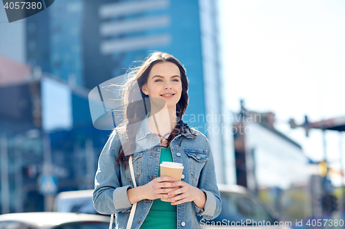 Image of happy young woman drinking coffee on city street