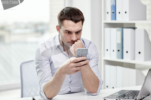 Image of businessman with smartphone and laptop at office