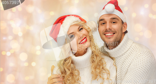 Image of happy family couple in sweaters and santa hats