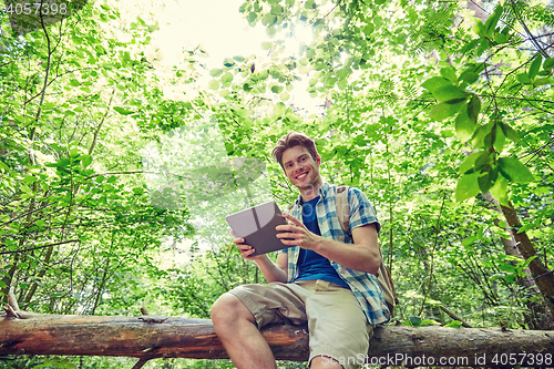 Image of happy man with backpack and tablet pc in woods