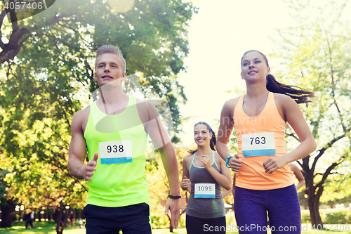 Image of happy young sportsmen racing wit badge numbers