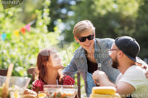 Image of happy friends having dinner at summer garden party