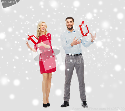 Image of happy couple with christmas gift boxes over snow