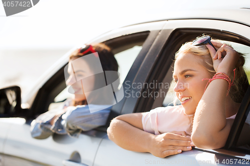 Image of happy teenage girls or women in car at seaside