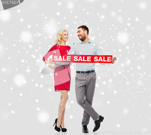 Image of happy couple with red sale sign over snow