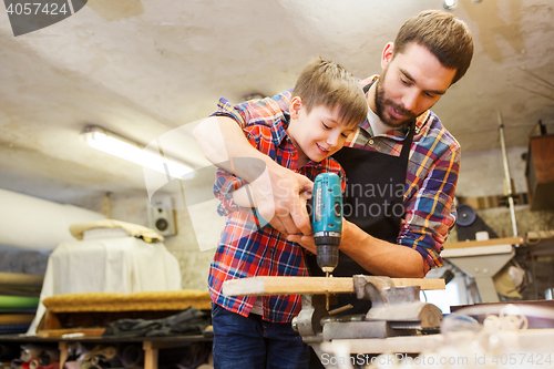 Image of father and son with drill working at workshop