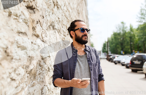 Image of man with smartphone at stone wall