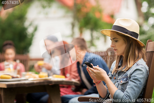 Image of woman with smartphone and friends at summer party