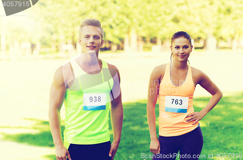 Image of happy friends or couple with racing badge numbers