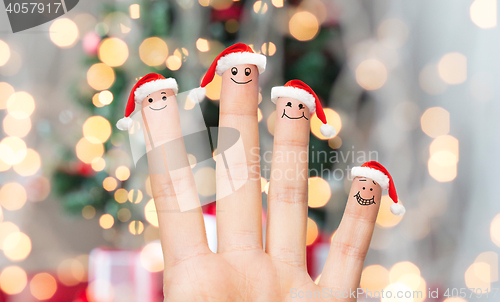 Image of close up of hand with four fingers in santa hats