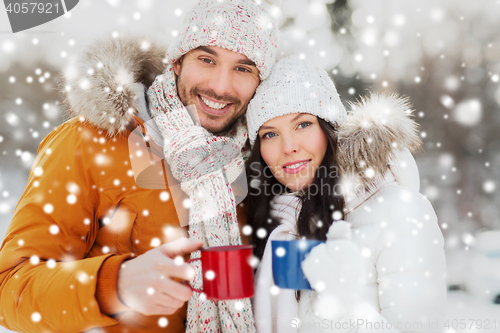 Image of happy couple with tea cups over winter landscape