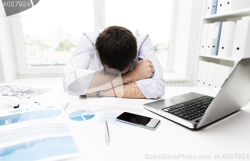 Image of businessman with laptop and papers in office