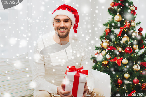 Image of happy man with christmas gift box at home