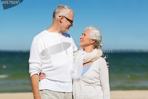 Image of happy senior couple hugging on summer beach