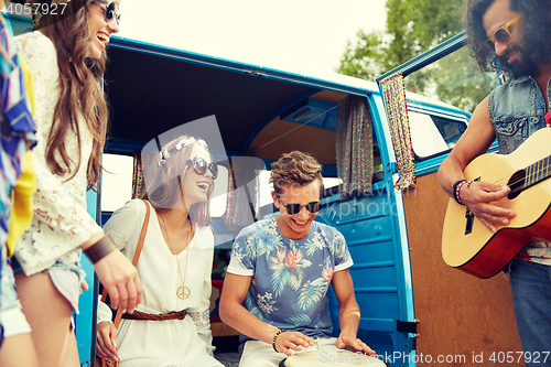 Image of happy hippie friends playing music over minivan