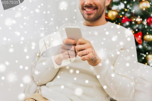 Image of smiling man with smartphone at home for christmas