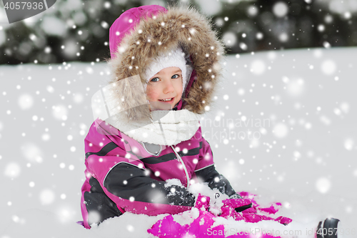 Image of happy kid in winter clothes playing with snow