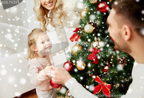 Image of happy family decorating christmas tree at home