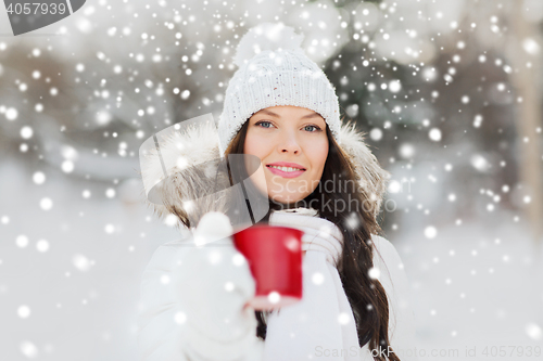 Image of happy young woman with tea cup outdoors in winter