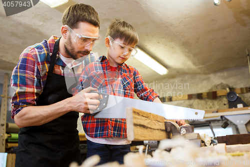 Image of father and son with saw working at workshop