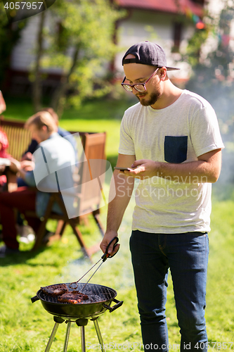 Image of man cooking meat on barbecue grill at summer party