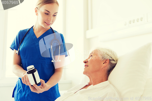 Image of nurse giving medicine to senior woman at hospital