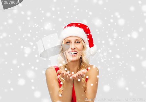 Image of happy woman in santa hat holding something on palm