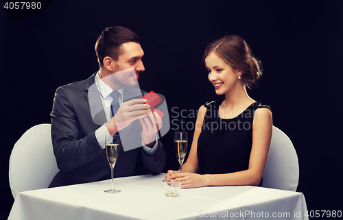 Image of excited young woman looking at boyfriend with box