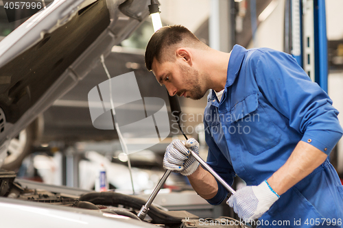 Image of mechanic man with wrench repairing car at workshop