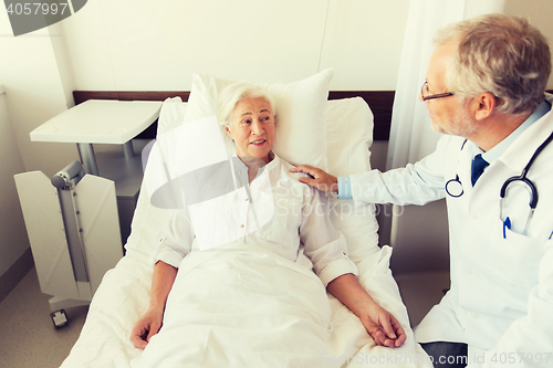 Image of doctor visiting senior woman at hospital ward