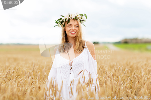 Image of happy young woman in flower wreath on cereal field