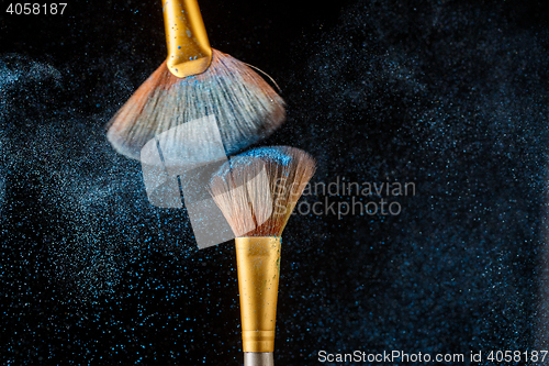 Image of Two brushes and blue scattered shadows at black background