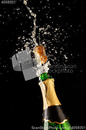 Image of Green champagne bottle with gold foil and cork explosion