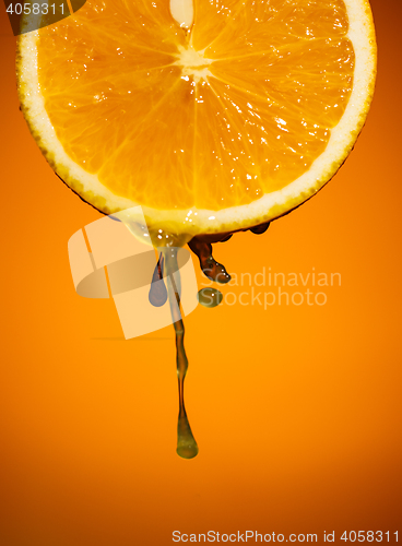 Image of Fresh orange slice with drops of juice close up on color background