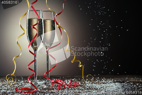 Image of Two champagne glasses on black background with backlight and snowfall