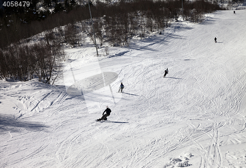 Image of Skiers and snowboarders on ski slope at sun winter day